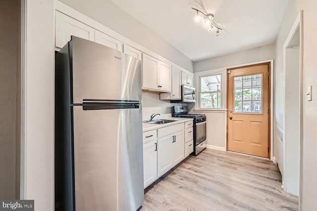 kitchen featuring sink, white cabinetry, stainless steel appliances, and light hardwood / wood-style flooring