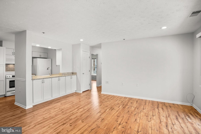 unfurnished living room featuring light hardwood / wood-style floors and a textured ceiling