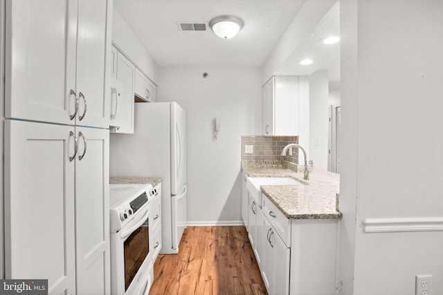 kitchen featuring white cabinets, hardwood / wood-style flooring, decorative backsplash, light stone countertops, and range with electric stovetop