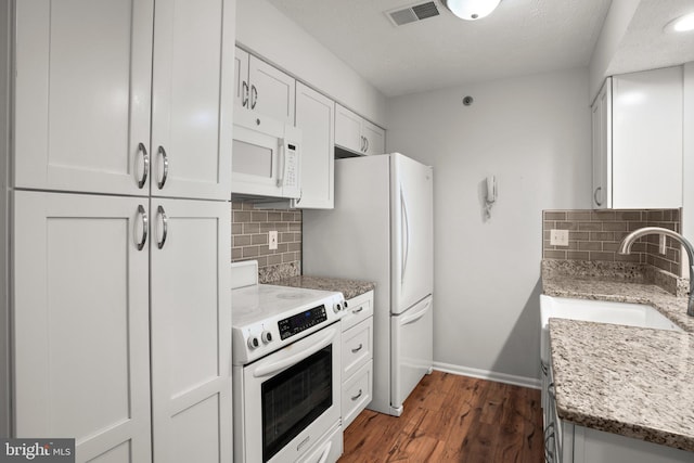 kitchen with white appliances, dark hardwood / wood-style flooring, light stone counters, white cabinets, and backsplash