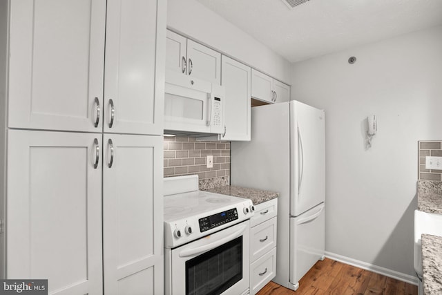 kitchen featuring white cabinets, light stone counters, white appliances, hardwood / wood-style floors, and backsplash