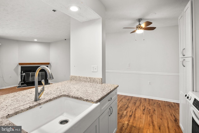 kitchen featuring sink, white cabinetry, light stone counters, and a textured ceiling