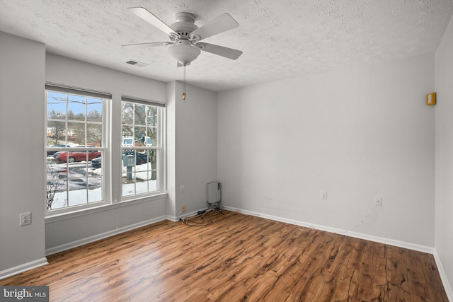 empty room with hardwood / wood-style flooring, a textured ceiling, and ceiling fan