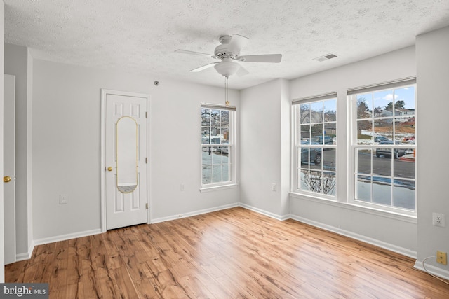 empty room with a textured ceiling, ceiling fan, and light hardwood / wood-style flooring