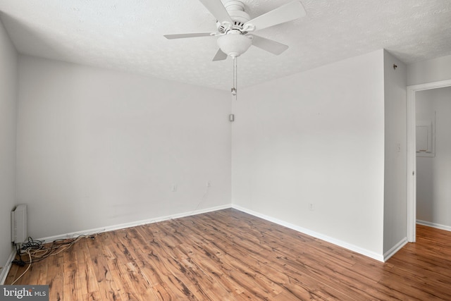 empty room featuring radiator heating unit, a textured ceiling, ceiling fan, and hardwood / wood-style flooring