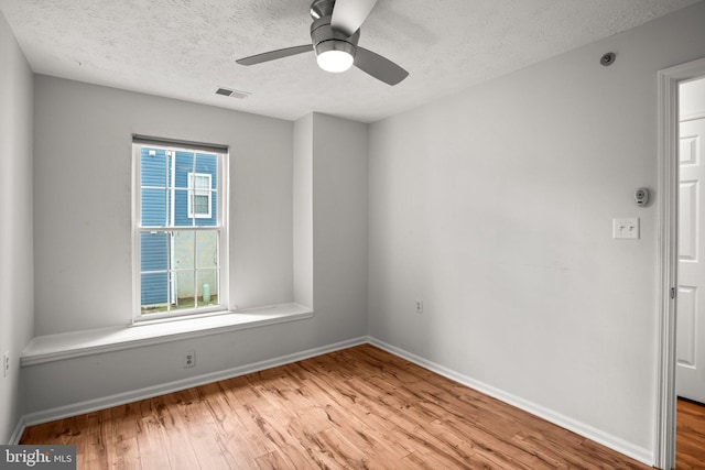 spare room featuring ceiling fan, light hardwood / wood-style flooring, and a textured ceiling