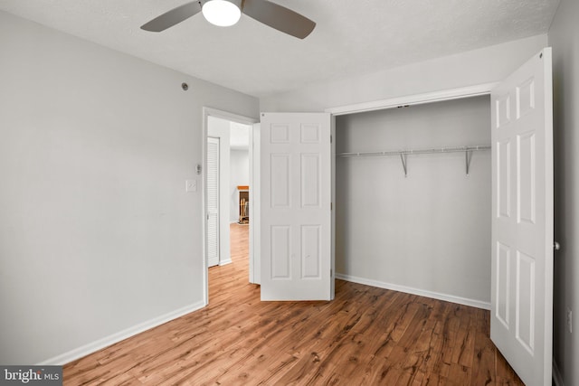 unfurnished bedroom with wood-type flooring, a closet, and ceiling fan