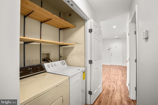 washroom with washing machine and dryer and light hardwood / wood-style floors