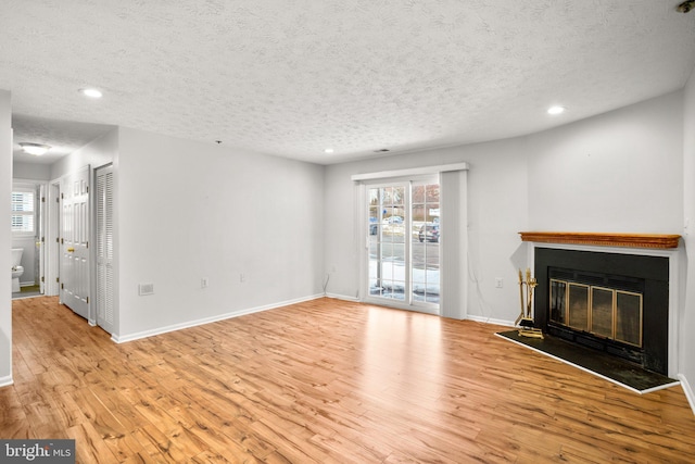 unfurnished living room featuring a textured ceiling, a healthy amount of sunlight, and light hardwood / wood-style floors