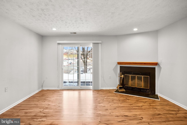 unfurnished living room with a textured ceiling and light hardwood / wood-style floors