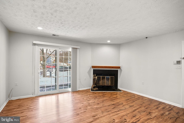 unfurnished living room featuring hardwood / wood-style flooring and a textured ceiling