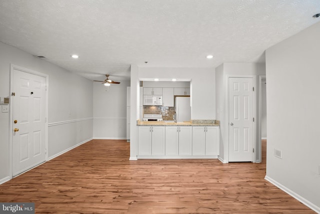 kitchen featuring white cabinets, light hardwood / wood-style flooring, decorative backsplash, and stainless steel refrigerator