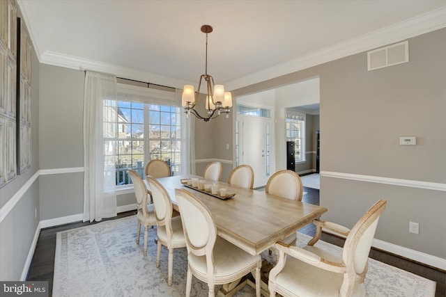 dining space featuring crown molding, dark hardwood / wood-style flooring, and an inviting chandelier