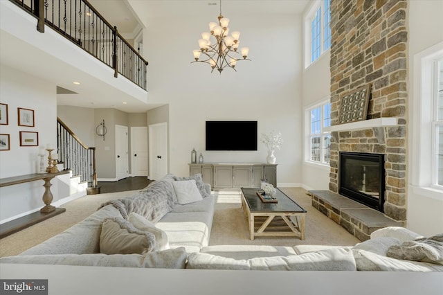 living room with a high ceiling, carpet, a chandelier, and a fireplace