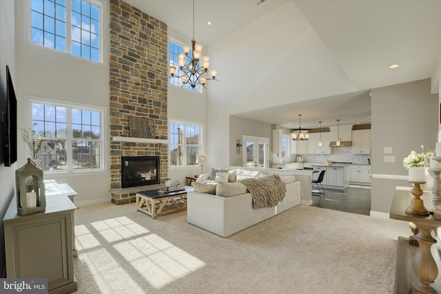 carpeted living room with a chandelier, a towering ceiling, and a stone fireplace