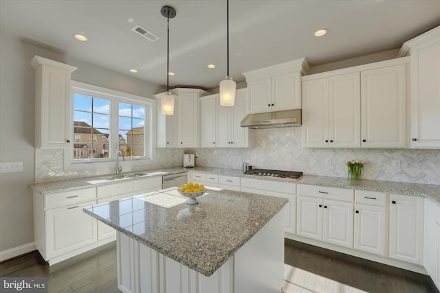 kitchen featuring white cabinetry, a center island, decorative light fixtures, and sink