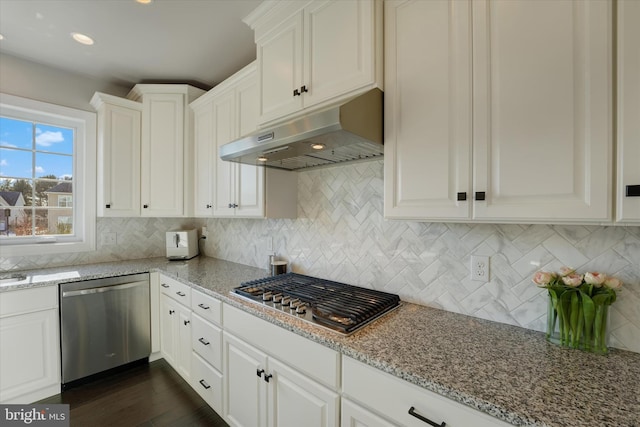 kitchen with backsplash, dark wood-type flooring, appliances with stainless steel finishes, white cabinets, and light stone counters