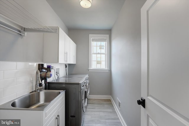 laundry area with cabinets, sink, independent washer and dryer, and light wood-type flooring