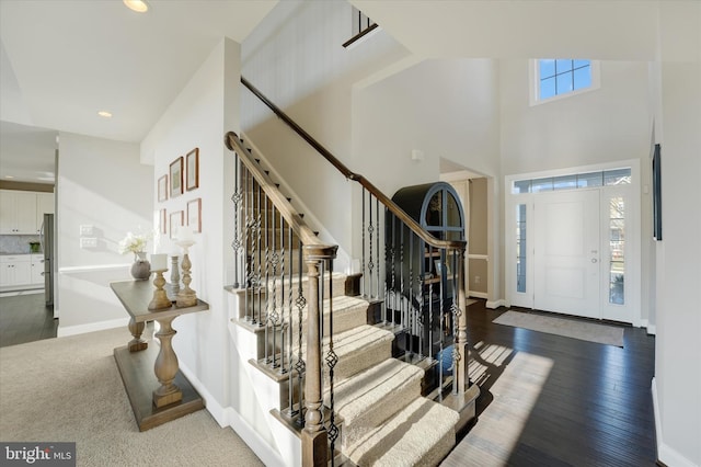 foyer entrance with a wealth of natural light, hardwood / wood-style floors, and a towering ceiling