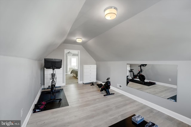 workout room with vaulted ceiling and light hardwood / wood-style floors