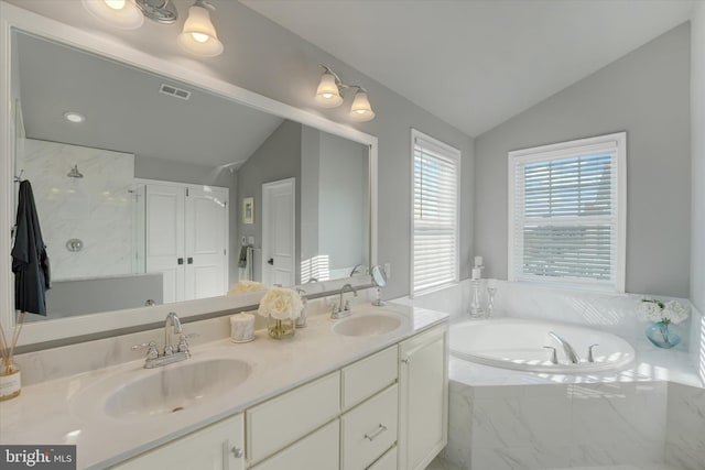 bathroom with vaulted ceiling, a relaxing tiled tub, and vanity