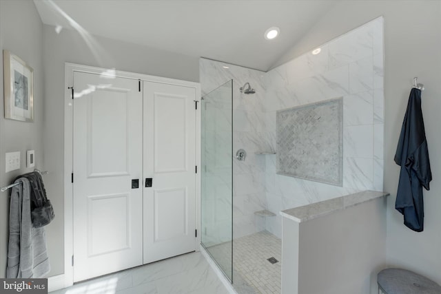 bathroom featuring vaulted ceiling and tiled shower