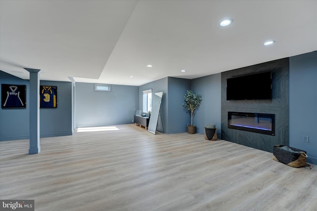 basement with a fireplace and light hardwood / wood-style flooring