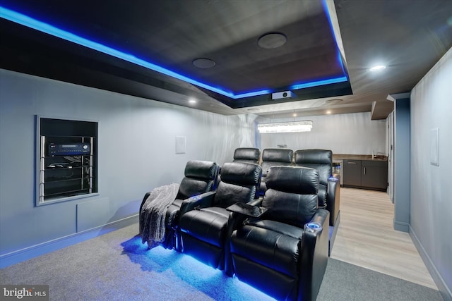 home theater with light hardwood / wood-style floors, indoor wet bar, and a tray ceiling