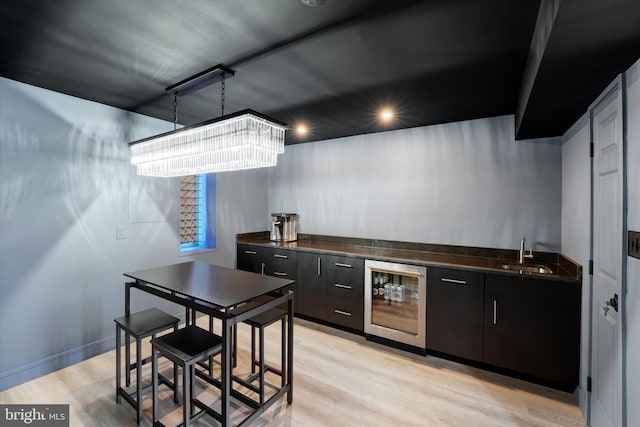 kitchen with sink, beverage cooler, and light hardwood / wood-style flooring