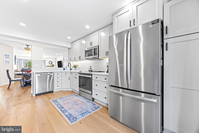 kitchen featuring stainless steel appliances, white cabinetry, ceiling fan, and light hardwood / wood-style flooring