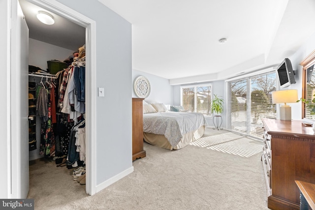 bedroom with light colored carpet, a closet, and a spacious closet