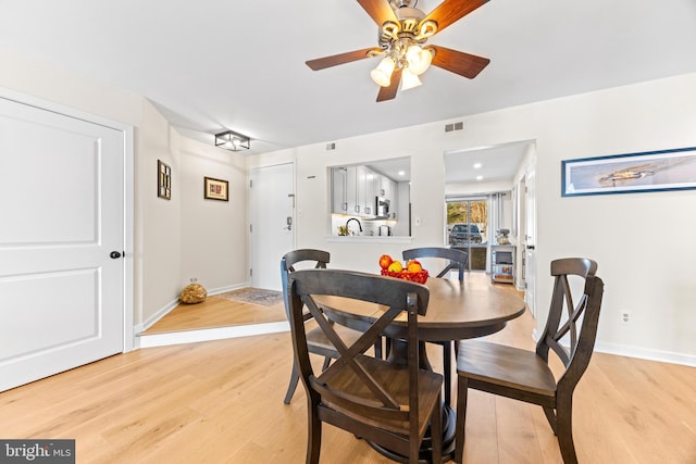 dining area with sink, light wood-type flooring, and ceiling fan