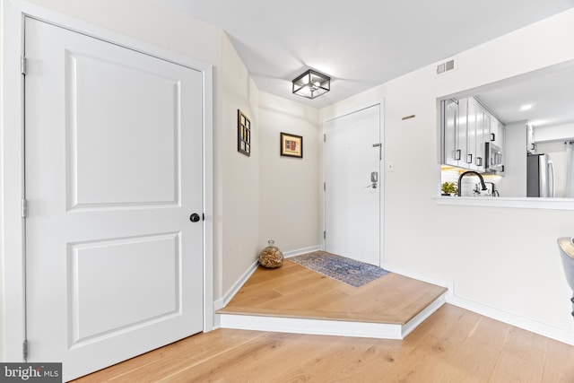 foyer entrance featuring sink and light hardwood / wood-style flooring