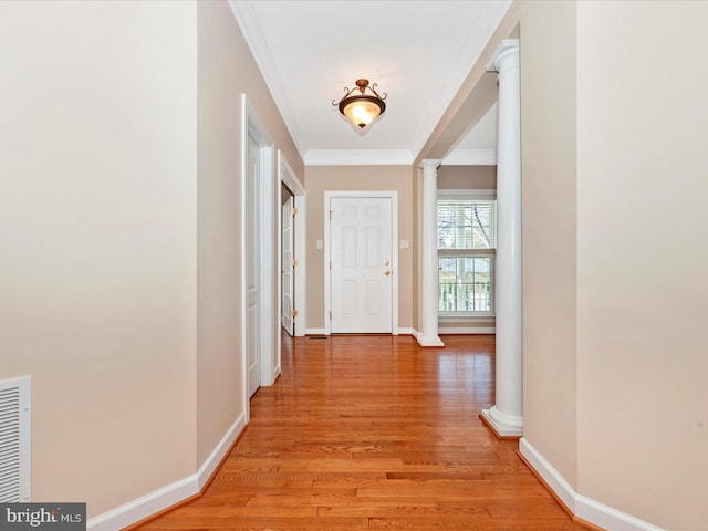 hall featuring light hardwood / wood-style flooring, crown molding, and ornate columns