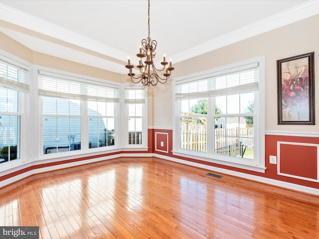 unfurnished room with a notable chandelier, a wealth of natural light, and hardwood / wood-style floors