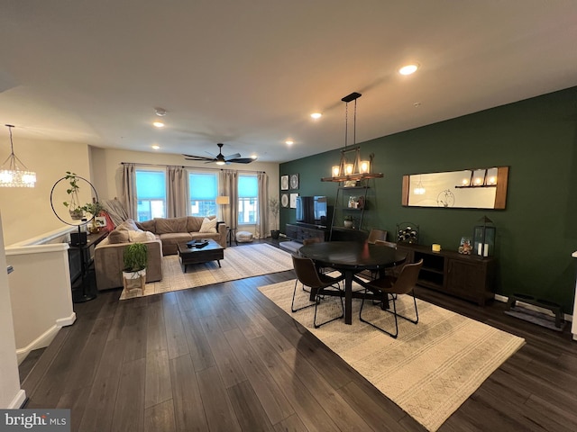 dining space featuring ceiling fan with notable chandelier and dark wood-type flooring