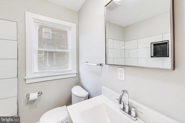 bathroom with plenty of natural light, toilet, and sink