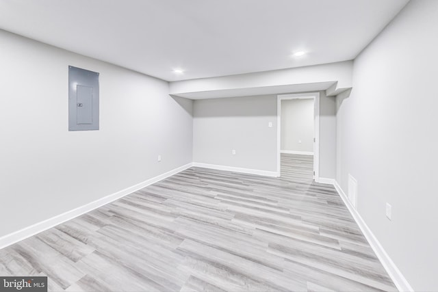 basement with light wood-type flooring and electric panel