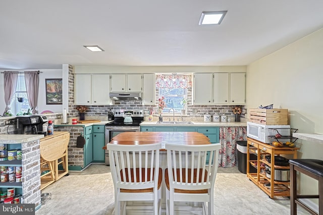 kitchen featuring a breakfast bar, backsplash, stainless steel electric range oven, and sink