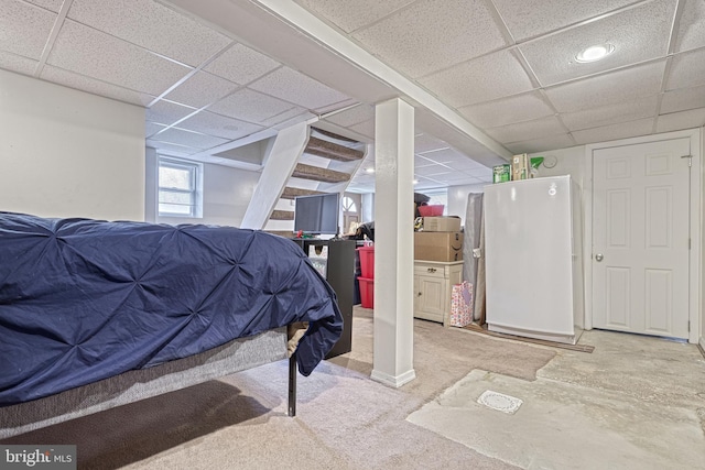 bedroom featuring a drop ceiling, white fridge, and carpet floors