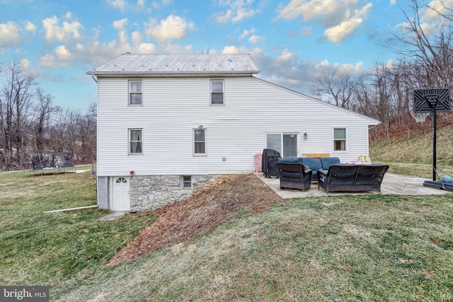 back of property featuring outdoor lounge area, a trampoline, a patio, and a lawn