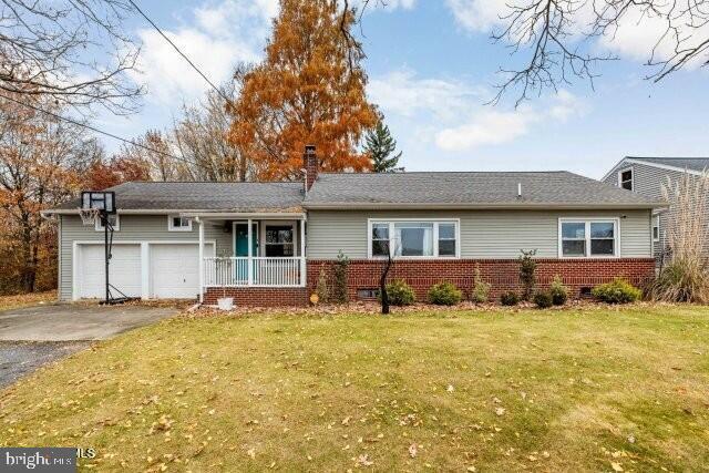 view of front of house featuring covered porch, a garage, and a front lawn