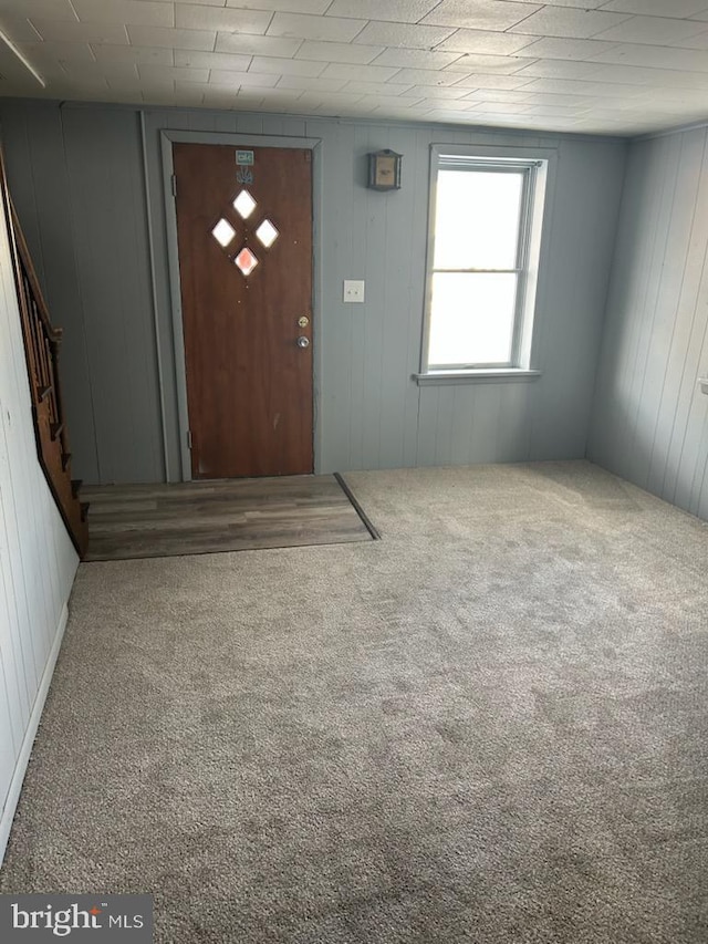 carpeted entrance foyer with wood walls