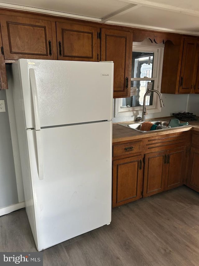 kitchen featuring white refrigerator, dark wood-type flooring, and sink