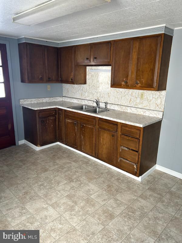 kitchen with dark brown cabinets, a textured ceiling, and sink