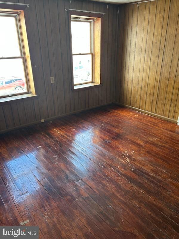 unfurnished room featuring dark wood-type flooring and wood walls