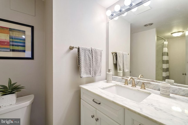 bathroom with toilet, a shower with shower curtain, and vanity