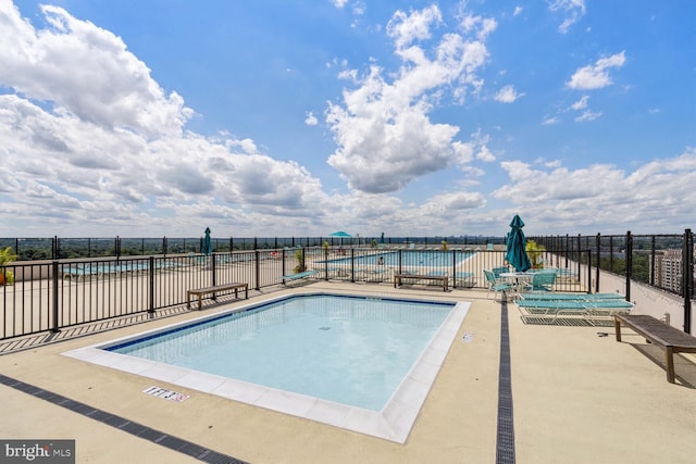 view of pool with a water view and a patio area