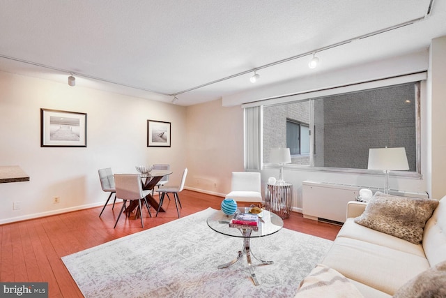 living room featuring hardwood / wood-style flooring, rail lighting, and a textured ceiling