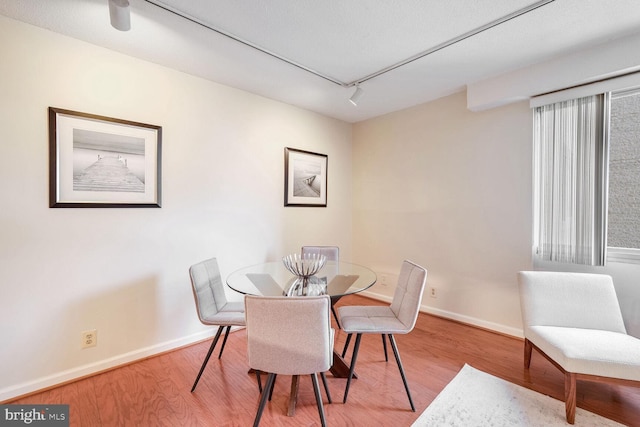 dining space with rail lighting and wood-type flooring